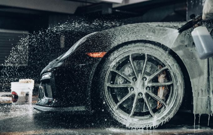 Mobile detailing in progress — foam wash on a black sports car